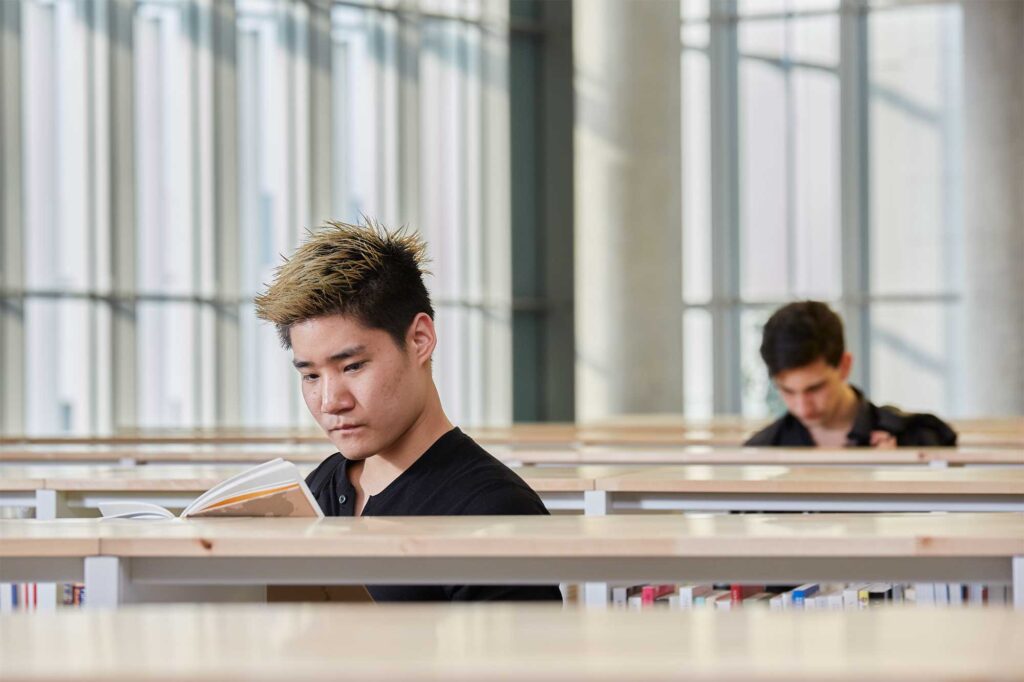 Two Underwood International College students browse the bookshelves in the library at Songdo campus, Yonsei University, Seoul, South Korea, searching for the perfect book.