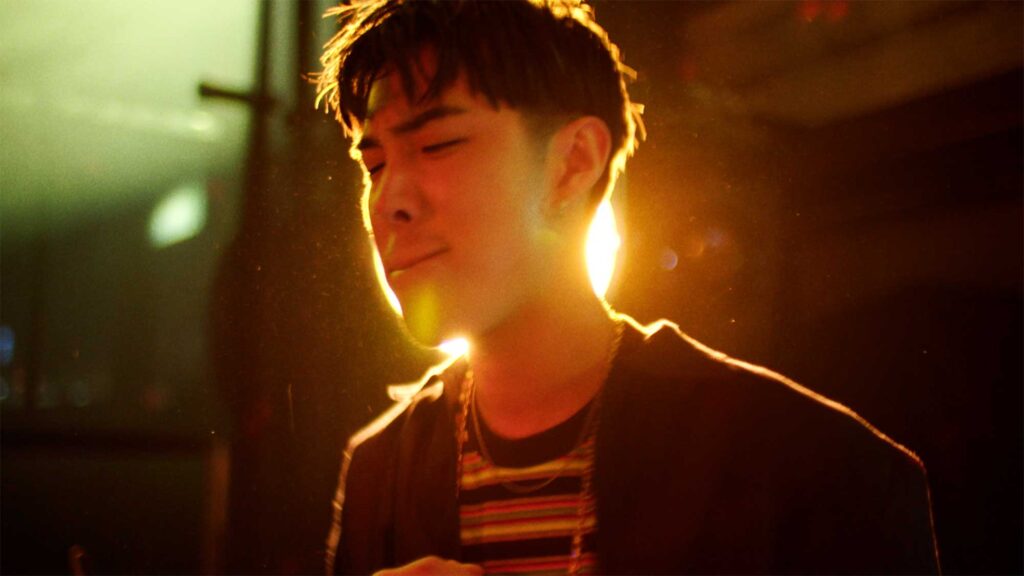 Korean rock musician backlit with warm light performing at bar Sonnendeck in Itaewon, Seoul, South Korea.