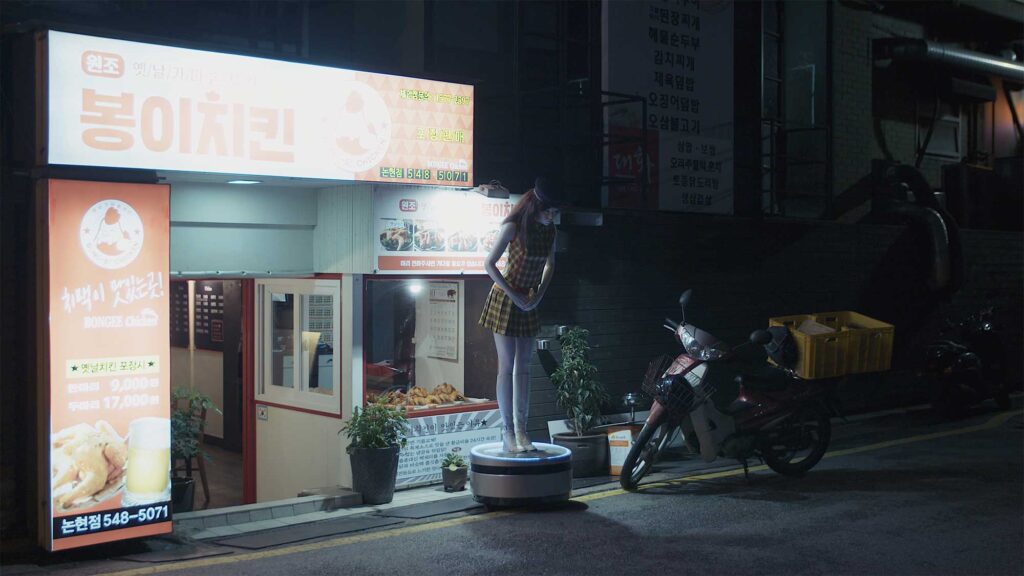 Close-up of plastic doll's face, shaped like human with makeup-like features, standing outside Korean motel as advertisement, Seoul, South Korea.