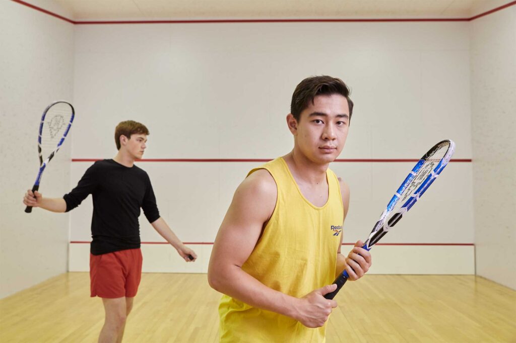 Two Underwood International College students playing squash on the Yonsei University Songdo campus, showcasing athleticism and camaraderie.