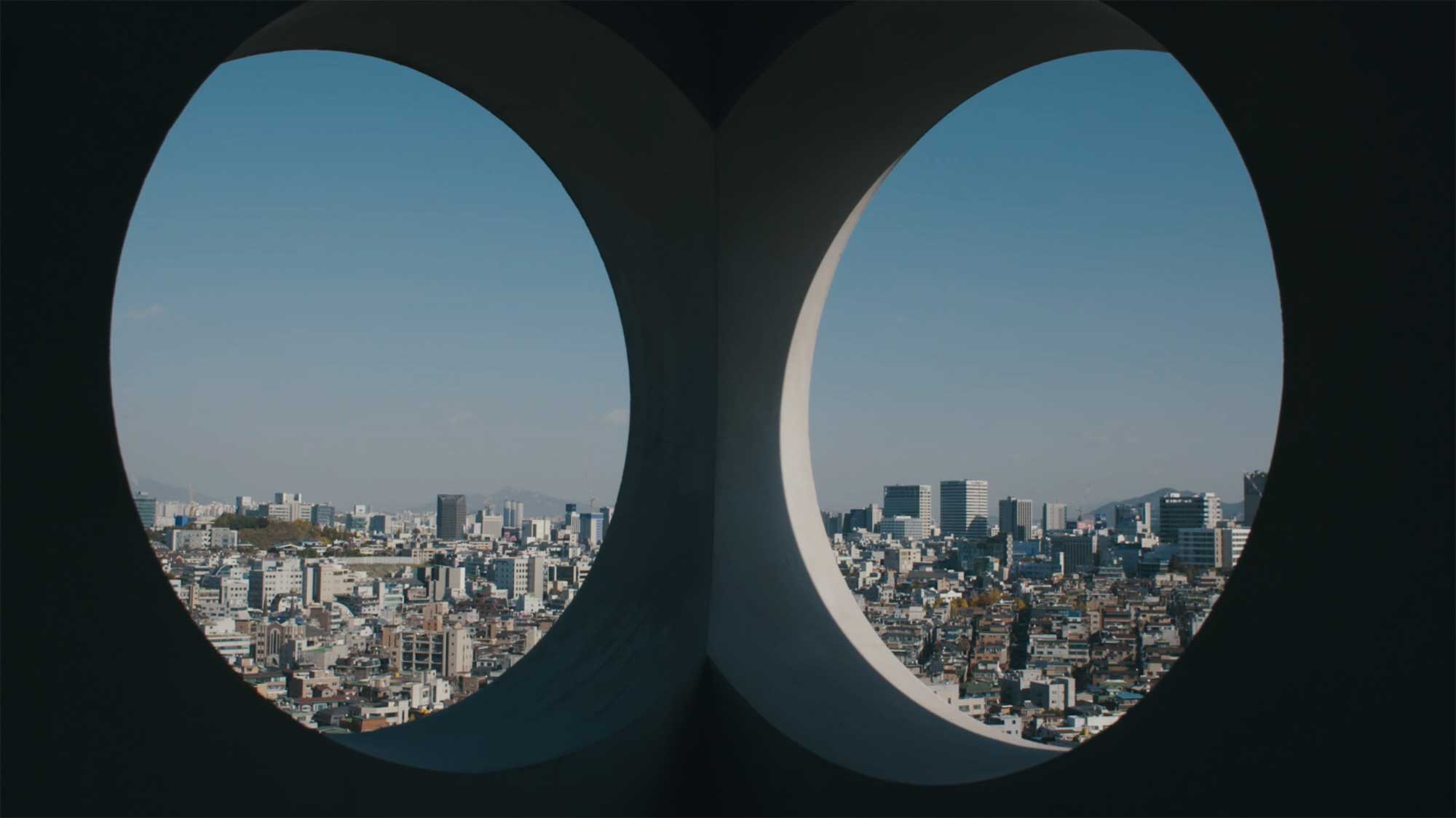 View through two round eye-shaped holes onto cityscape of Seoul, South Korea, in Gangnam district.