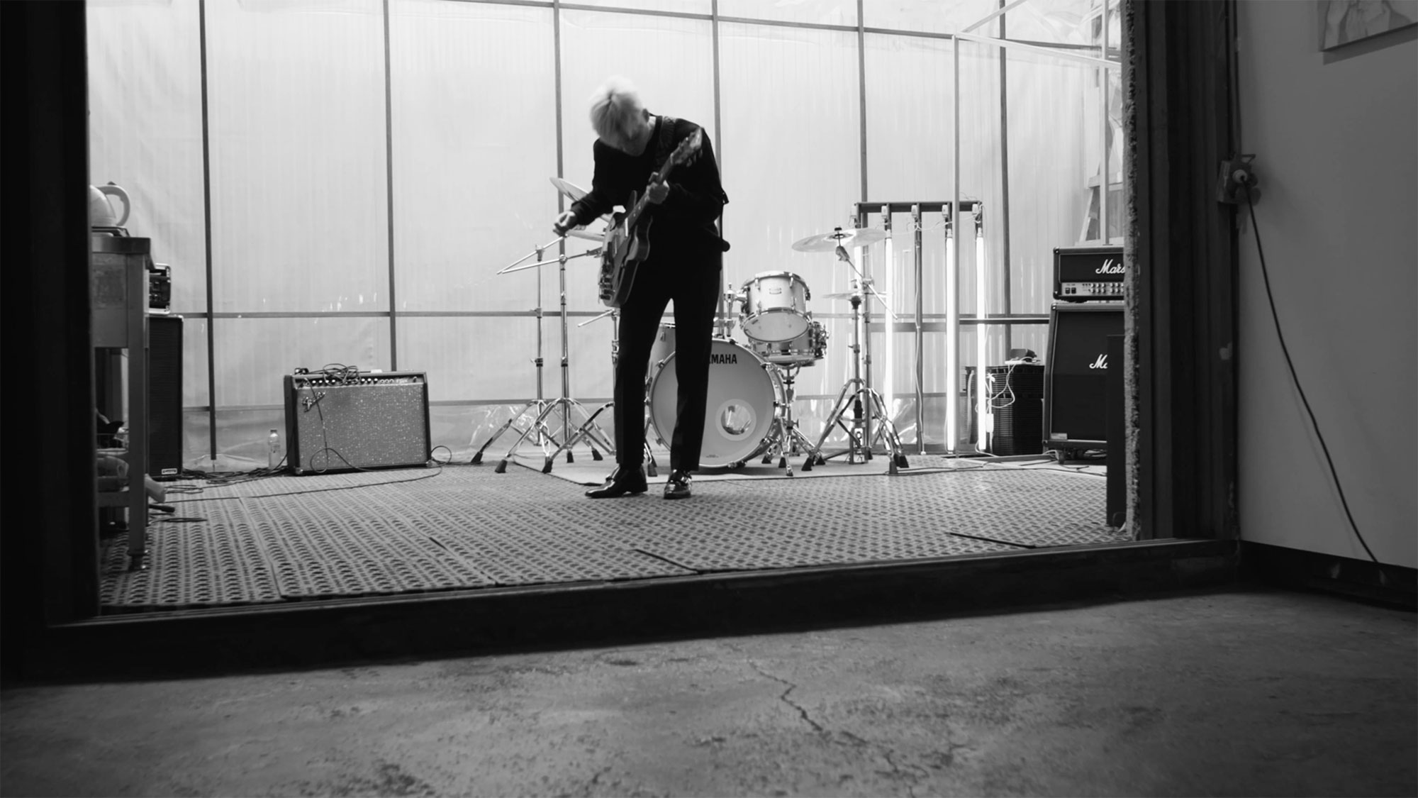 Young Korean musician plays guitar in winter garden extension of building in Seoul, South Korea, for music video "Beautiful Woman" from Tune-Up Joong-Hyun Shin: Origin tribute album.