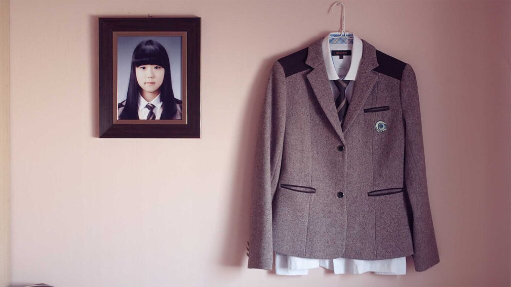 A school uniform hangs beside a portrait of a child who lost her life in the Sewol ferry disaster, a tragedy that claimed many lives in South Korea.