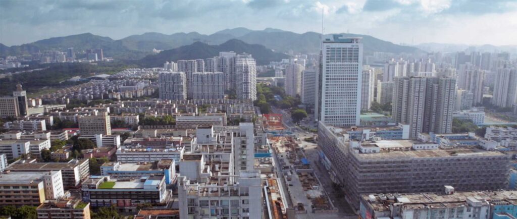 A sprawling view of Shenzhen, China, showcasing newly built high-rise architecture set against a dramatic mountain landscape.