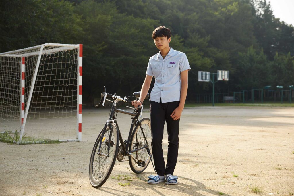 A student in uniform poses with his bicycle on the sports ground of Gwangyang Jecheol Middle & High School in Gwangyang, South Korea.