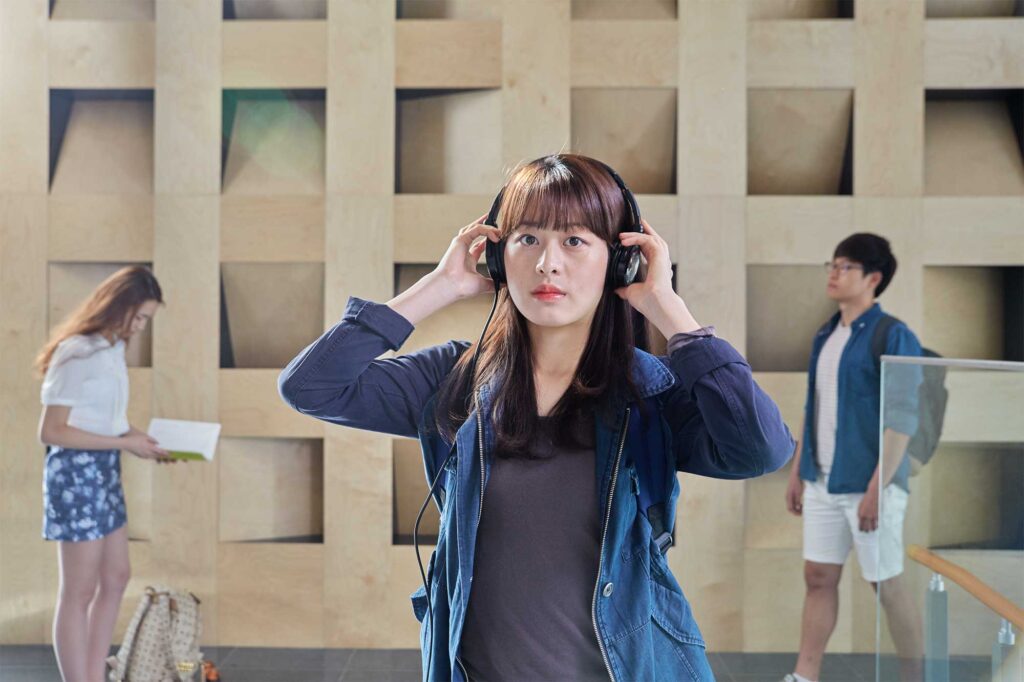 An Underwood International College student in a hall at Yonsei University Songdo campus, putting on her headphones and taking a break after class.