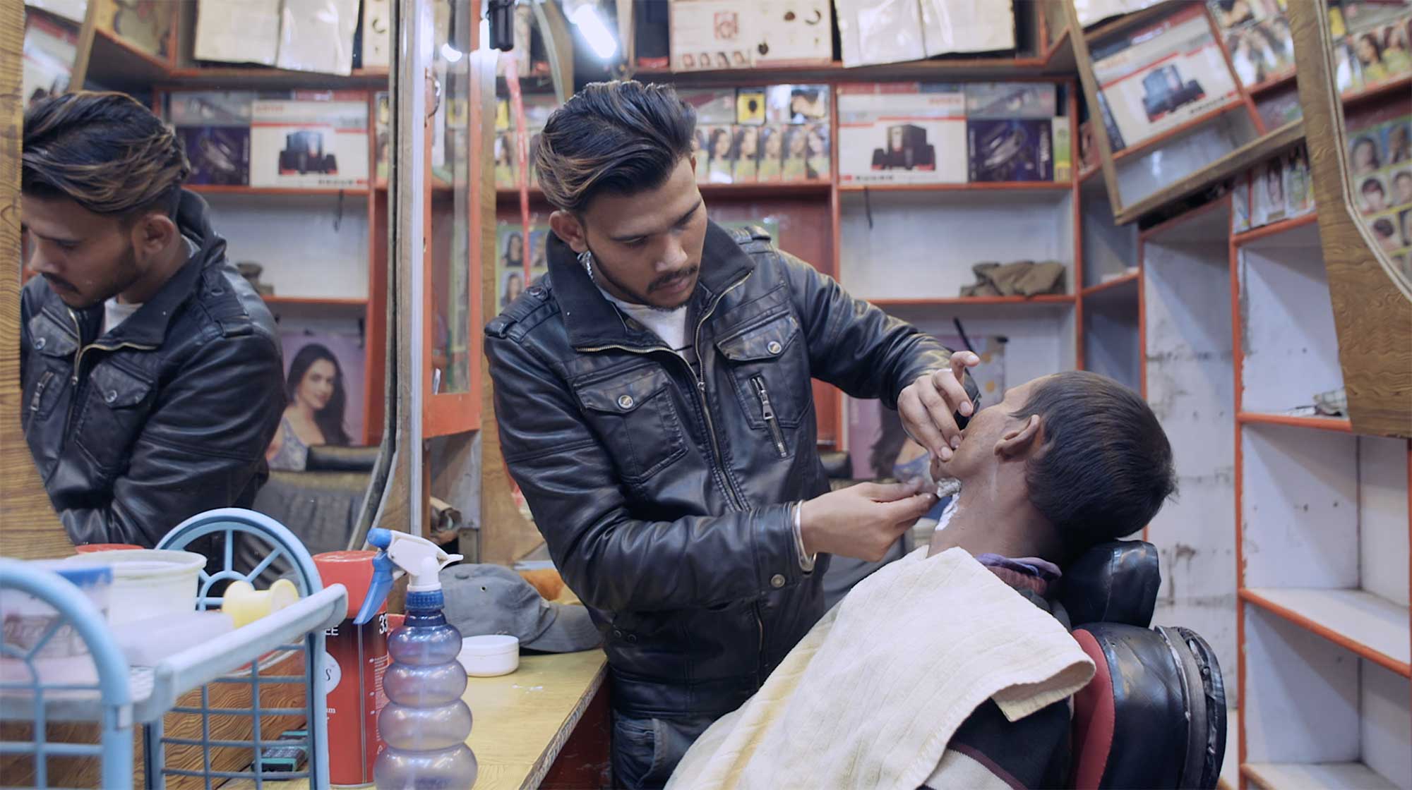 A barber in Leh, Ladakh, India, swiftly gives a morning shave to a customer with a knife, showcasing his skillful hands.