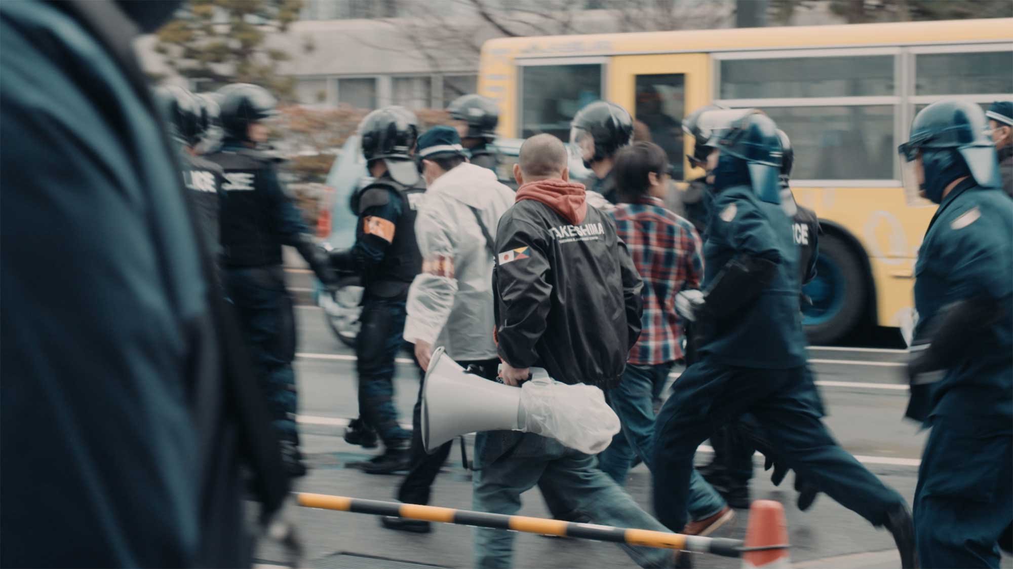 Japanese Takeshima activists run after a bus carrying Korean Dokdo activists, who are locked away by Japanese police to avoid violence during the protest in the film This Island is Ours.