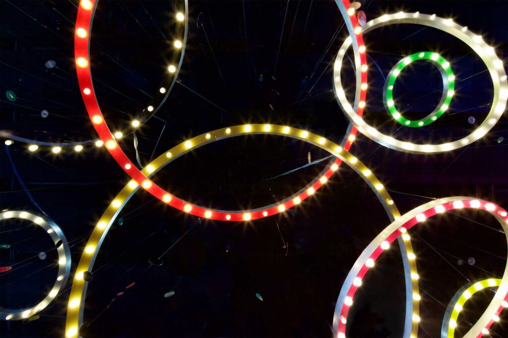 Mioon installation with circles of color and light in varying sizes hang from dark ceiling at SUPER-SPREADER MEDIA VIRUS exhibition, Nam June Paik Art Center, Seoul, South Korea.
