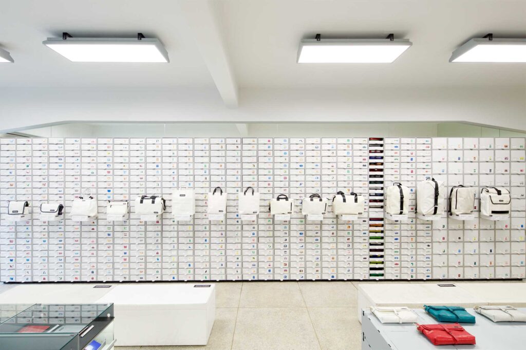 Shelf with built-in storage drawers at Freitag MMMG Seoul, South Korea, showcasing a sleek collection of black and white bags in a clean, minimalist display.