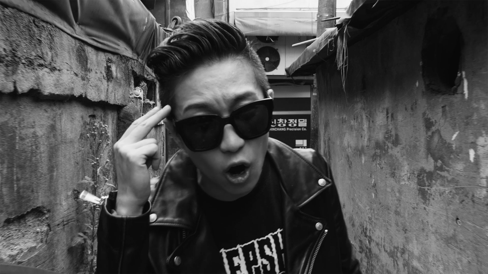 Singer in alleyway in Seoul, South Korea, singing towards camera for music video "Beautiful Woman" from Tune-Up Joong-Hyun Shin: Origin tribute album.