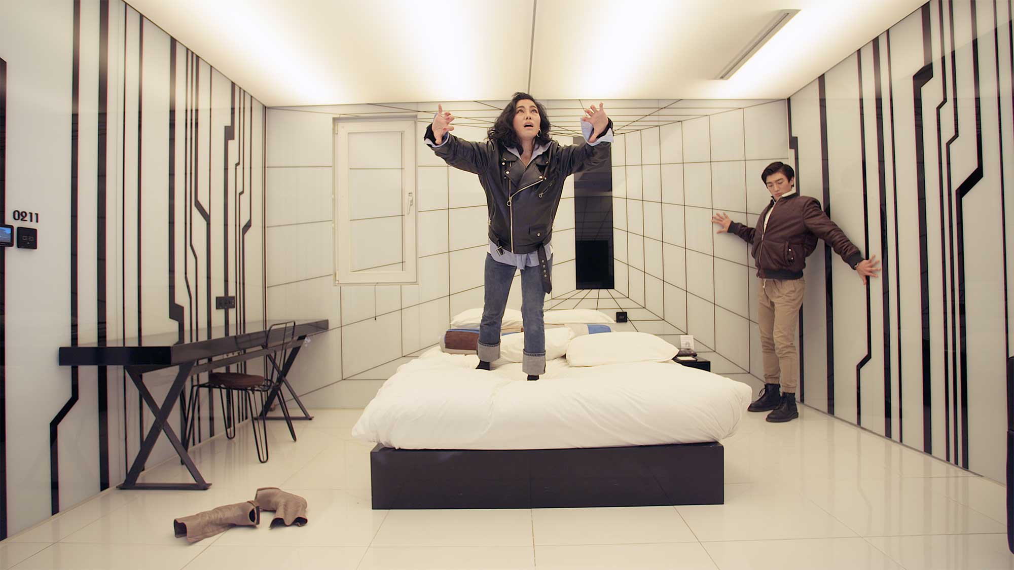 A young couple tries to tune in and connect with the atmosphere of a futuristic-looking motel room in Seoul, South Korea.