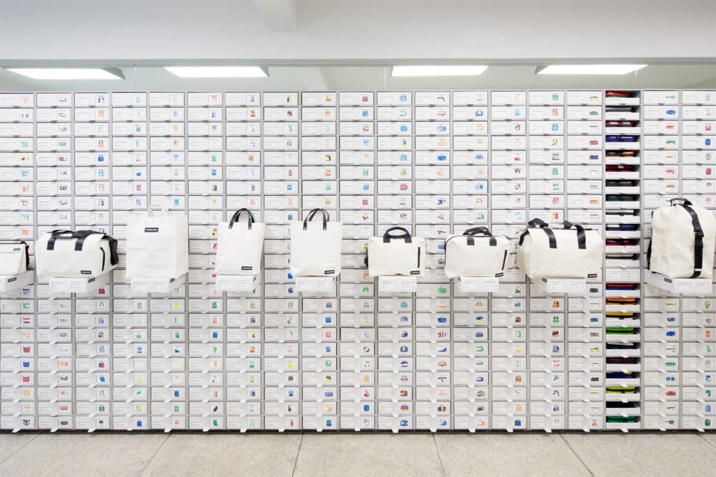 Close-up of shelf with built-in storage drawers at Freitag MMMG Seoul, South Korea, highlighting sleek collection of black and white bags in minimalist display.