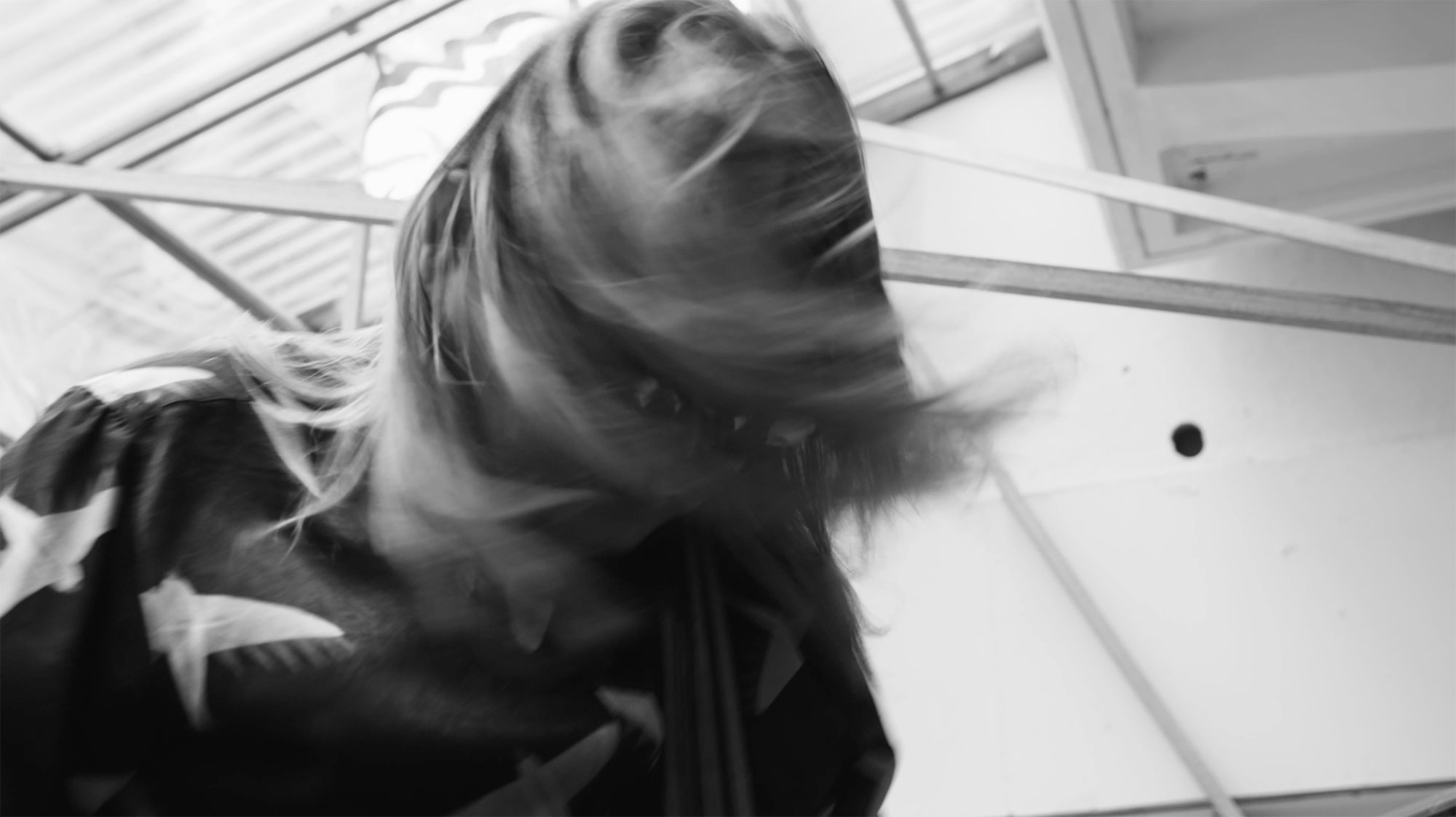 Korean musician rocking head and shaking long hair while performing in winter garden extension of building in Seoul, South Korea, for music video "Beautiful Woman" from Tune-Up Joong-Hyun Shin: Origin tribute album.