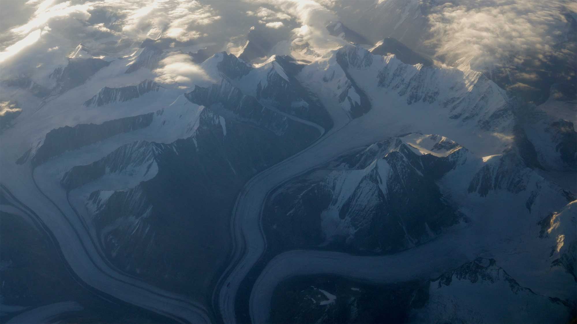 Snow-topped peaks and glaciers flow down the majestic Himalayas surrounding Ladakh, India, creating a breathtaking landscape.