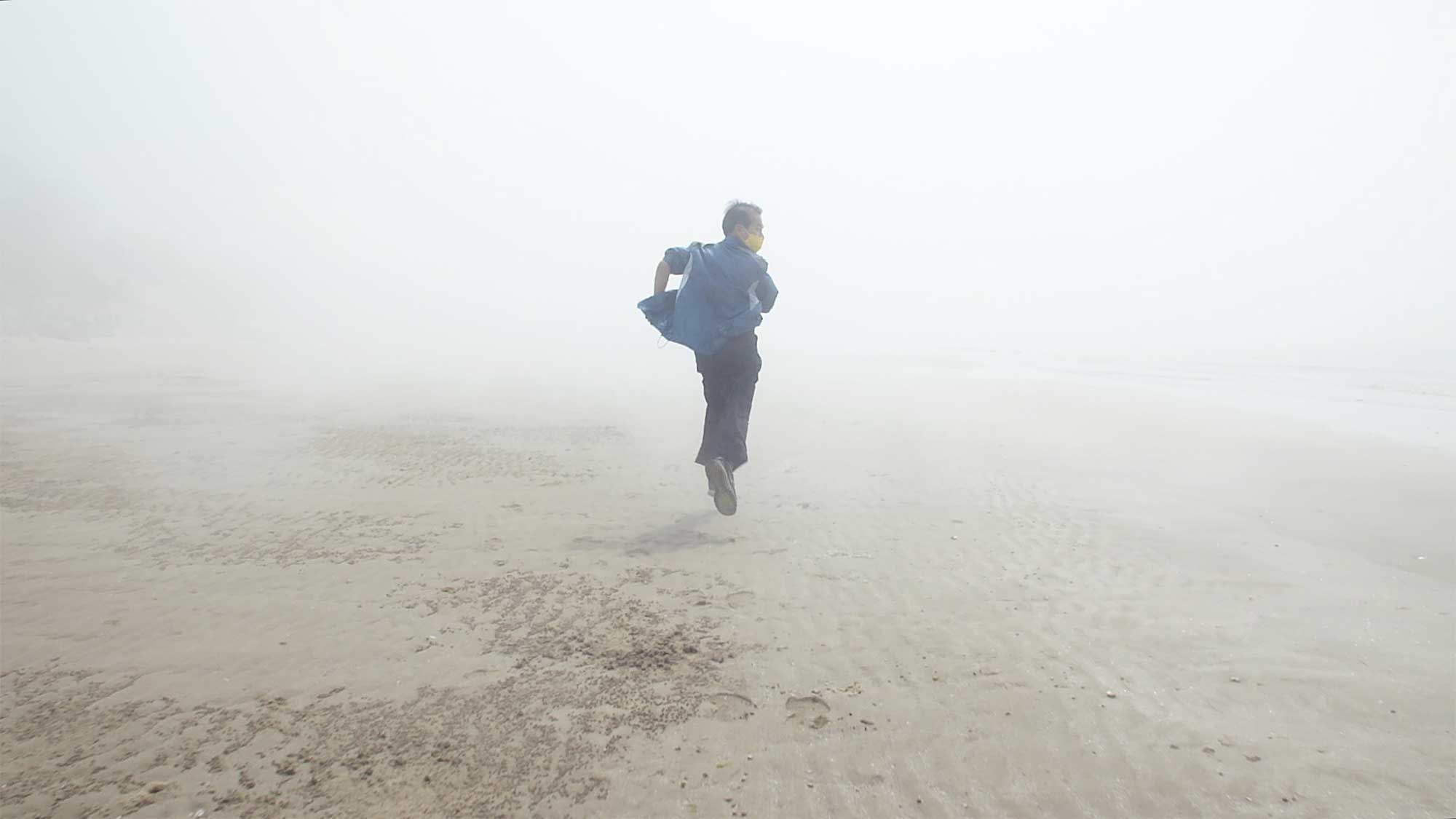 A man runs away from the camera on a fog-covered, lonely beach, resembling one of the lost souls of the Sewol ferry disaster in this dream sequence for the short film Last Letters.