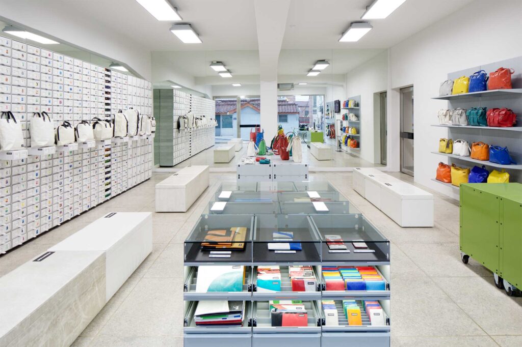 Wide shot of Freitag store interior at MMMG Seoul, South Korea, showcasing sleek collection of bags and accessories neatly arranged on shelves, reflecting minimalist design.