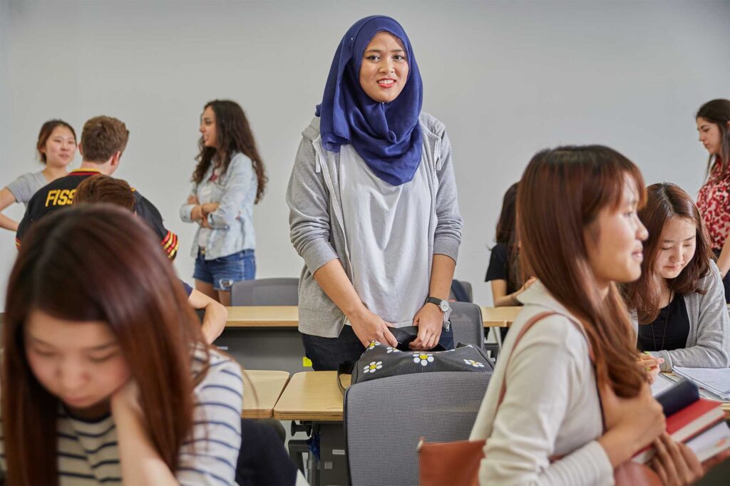 An Underwood International College student standing in a classroom at Yonsei University Songdo campus, getting ready for the upcoming class.