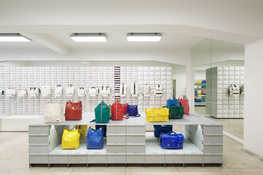 Freitag MMMG Seoul, South Korea, features a shelf with black and white bags in minimalist display (background) and a vibrant selection of colorful bags (foreground).