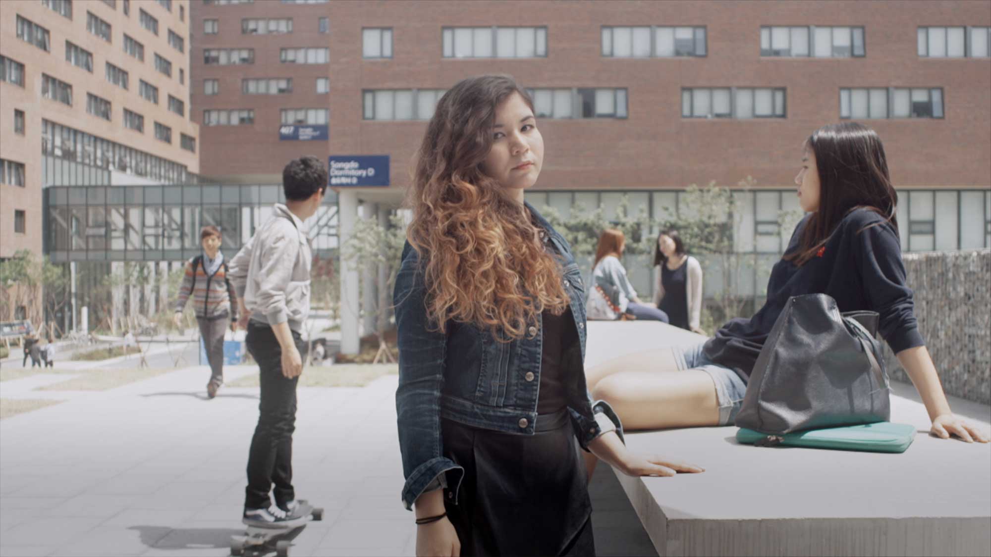 An Underwood International College student outside in an outdoor chill zone at Yonsei University Songdo campus, ready to join friends for a break between classes.