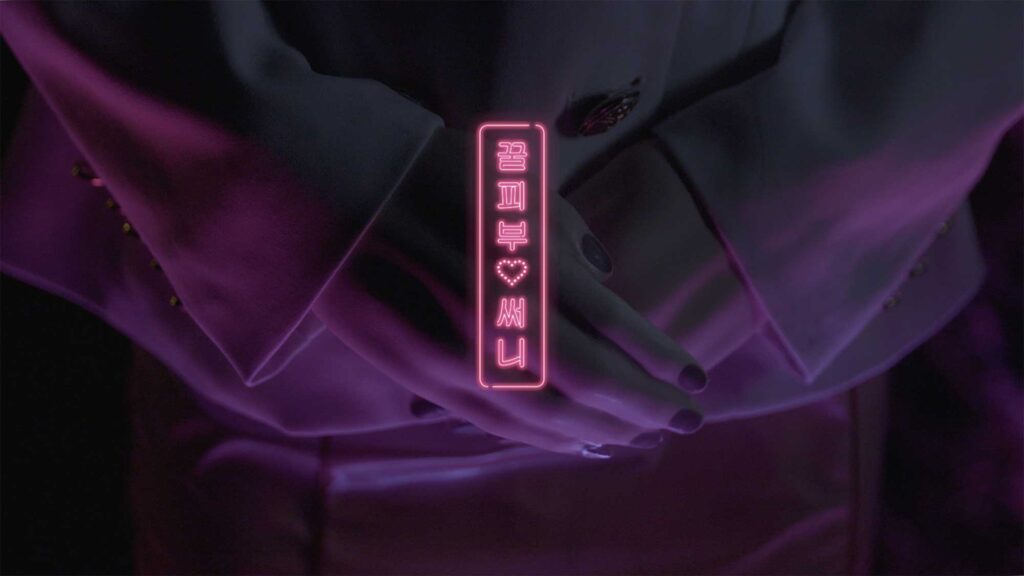 Close-up of hands of plastic doll with human traits, with graphic overlay displaying her name Sunny and characteristic Honey Skin as part of film Plastic Girls in Seoul, South Korea.