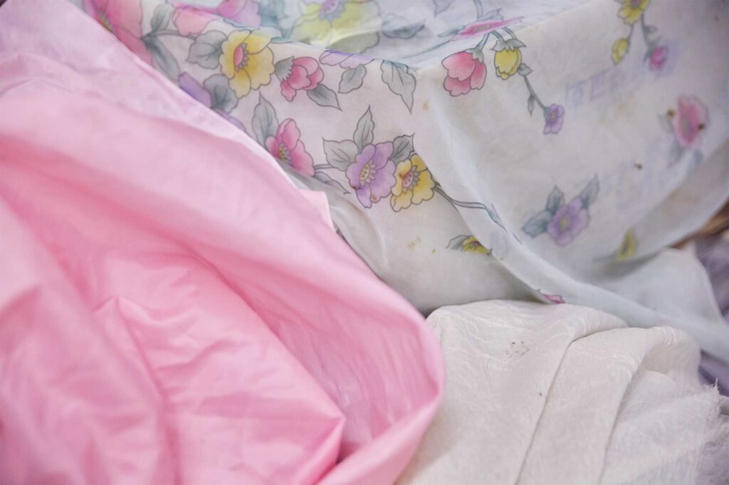 Different textured and colored hairdressing capes in a Seoul hairdresser shop, featured in AS IT IS magazine's issue on the beauty of aging.