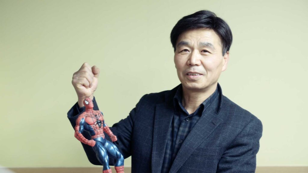 A Korean Dokdo activist holds a Spiderman figure to the camera, flexing his fist and biceps to illustrate the strength needed for the island dispute between Korea and Japan in the film This Island is Ours.