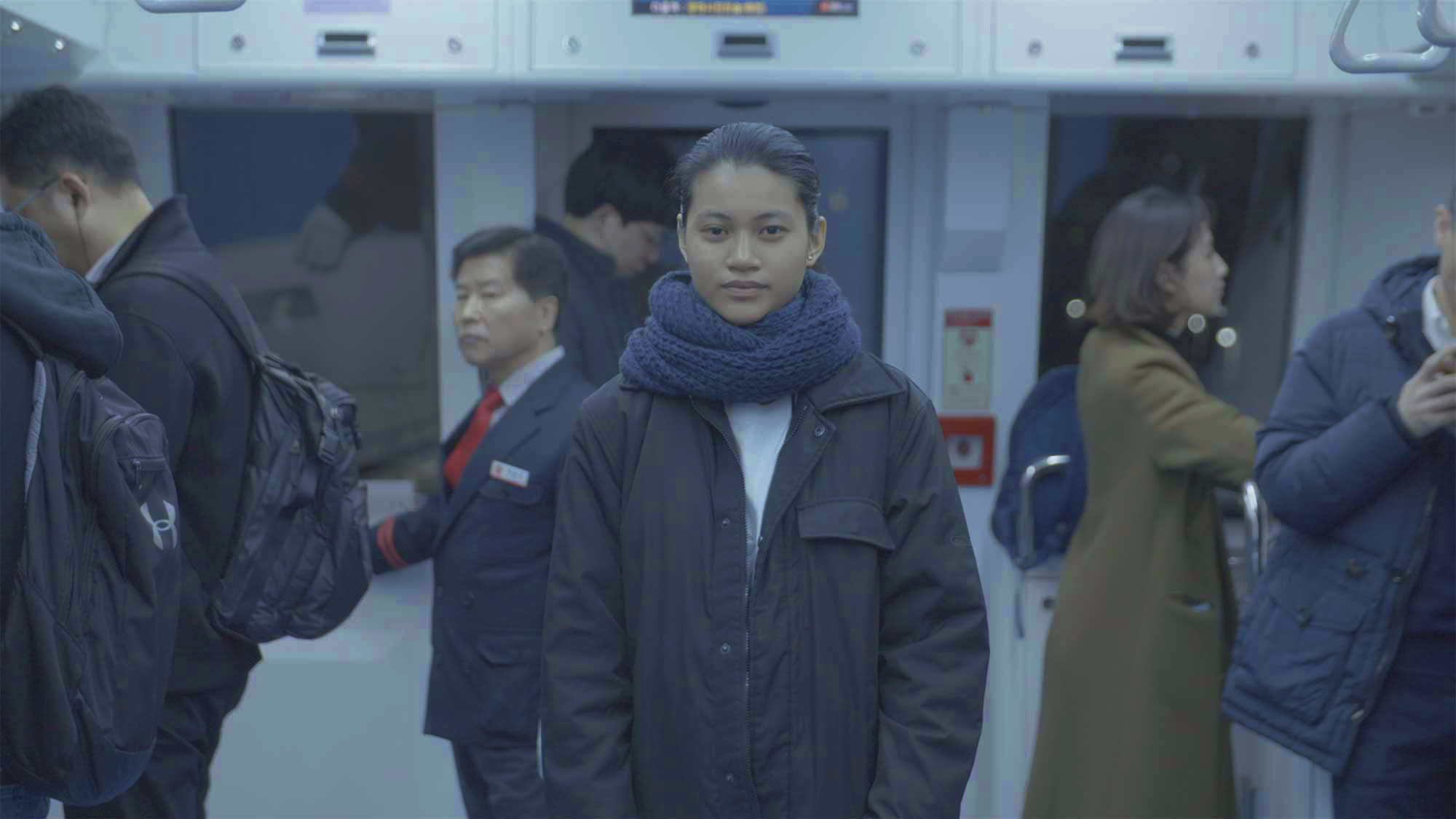 Minerva University student stands in middle of front cabin of subway in Seoul, South Korea, as it moves through tunnel.