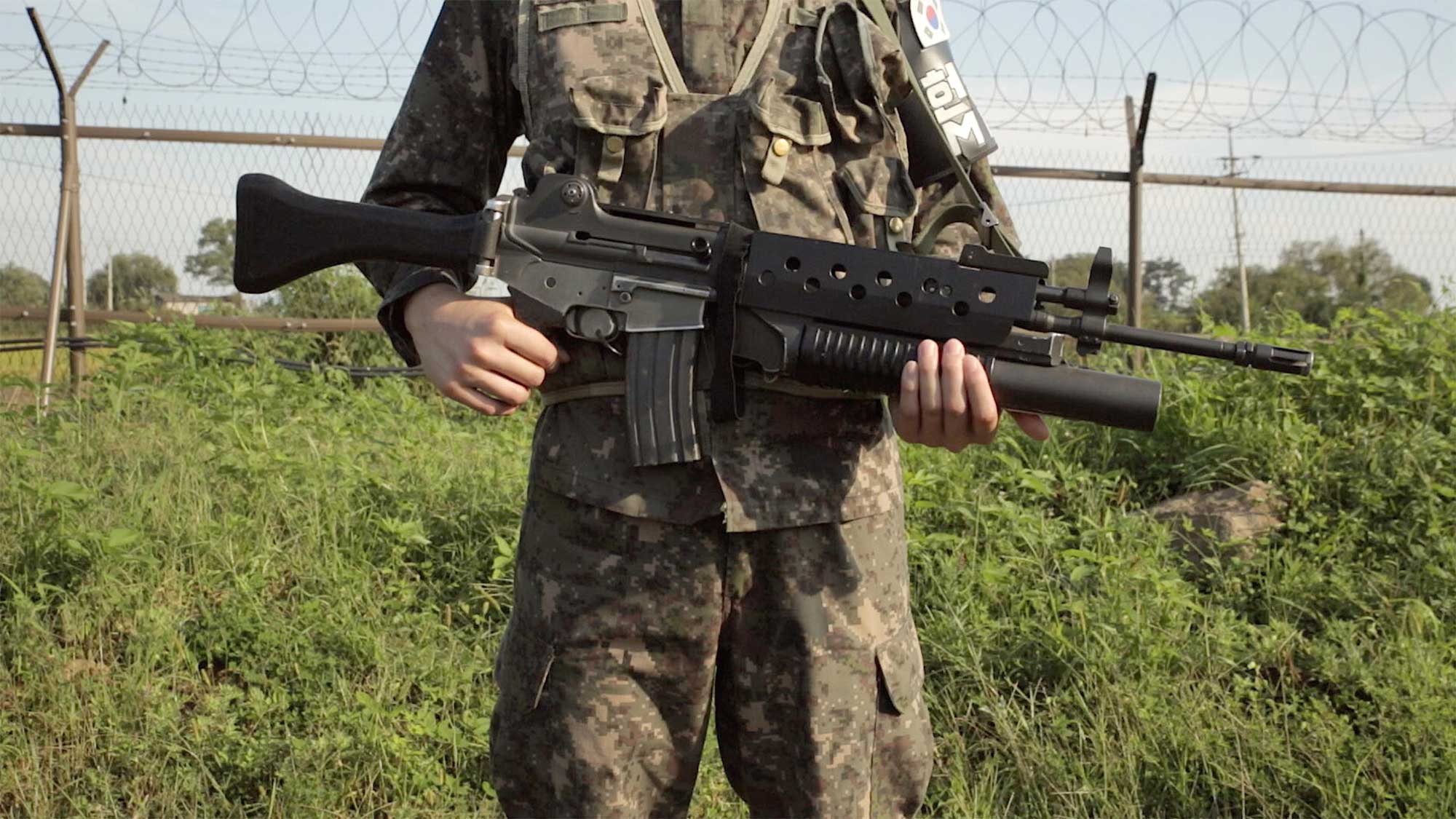 Two soldiers near DMZ close to Cherwon, Kangwando Province, South Korea, holding machine gun in both hands on guard in short film ART ATTACK.