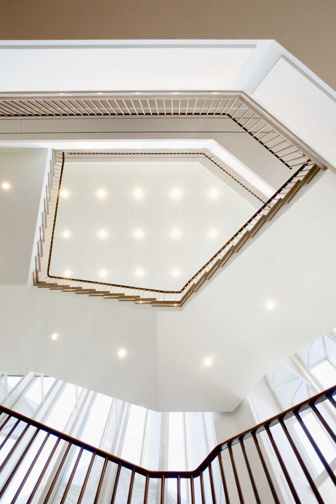 A bottom-to-top view highlights the empty space as the core element of the main staircase that elegantly spirals around the interior of The Burberry Flagship Store in Seoul, South Korea.