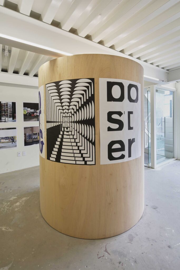 A round pillar in the center of the exhibition space adorned with two posters for the poster exhibition in Seoul, South Korea, by Graphic Magazine as part of Propaganda Press.