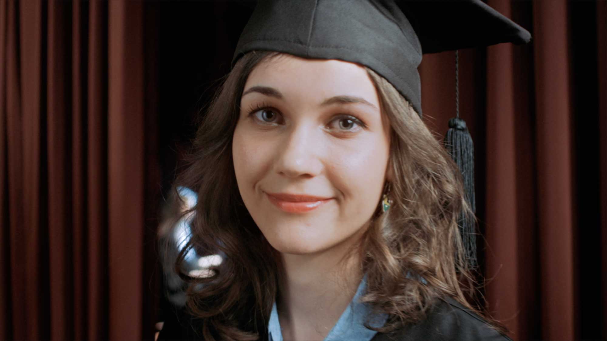 An Underwood International College student on stage in a large auditorium at Yonsei University Songdo campus, joyfully celebrating her graduation.