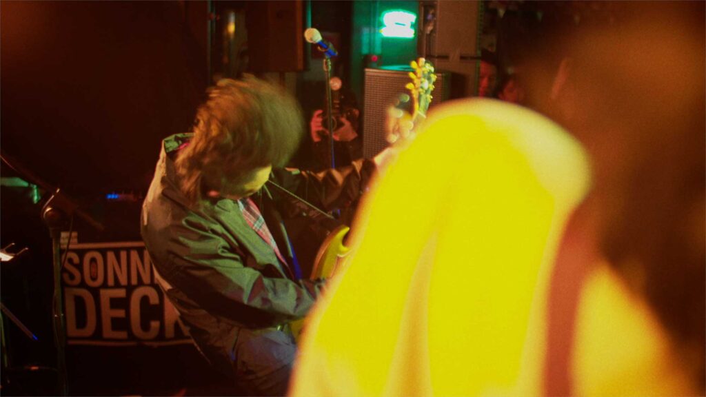 Korean rock guitarist in warm lighting, playing during performance at Sonnendeck bar in Itaewon, Seoul, South Korea.