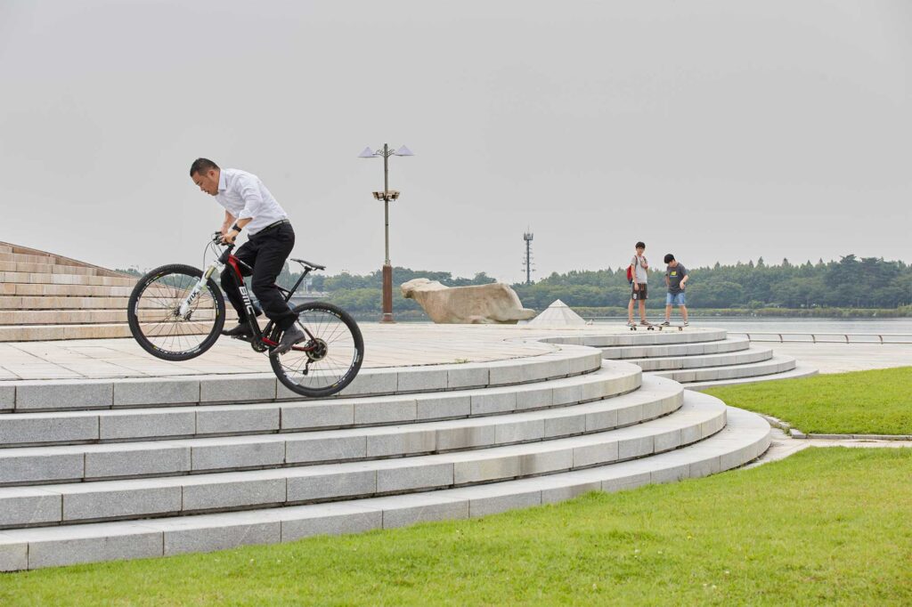 Lee Jaeyong performs tricks on his mountain bike, leaping up a staircase while dressed in his office attire, showcasing his unique style in Seoul, South Korea.