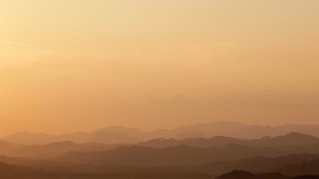 Orange-bathed mountain landscape at sunset overlooking DMZ near small village Yangjiri, Cherwon, Kangwando Province, facing North Korean territory in short film ART ATTACK.