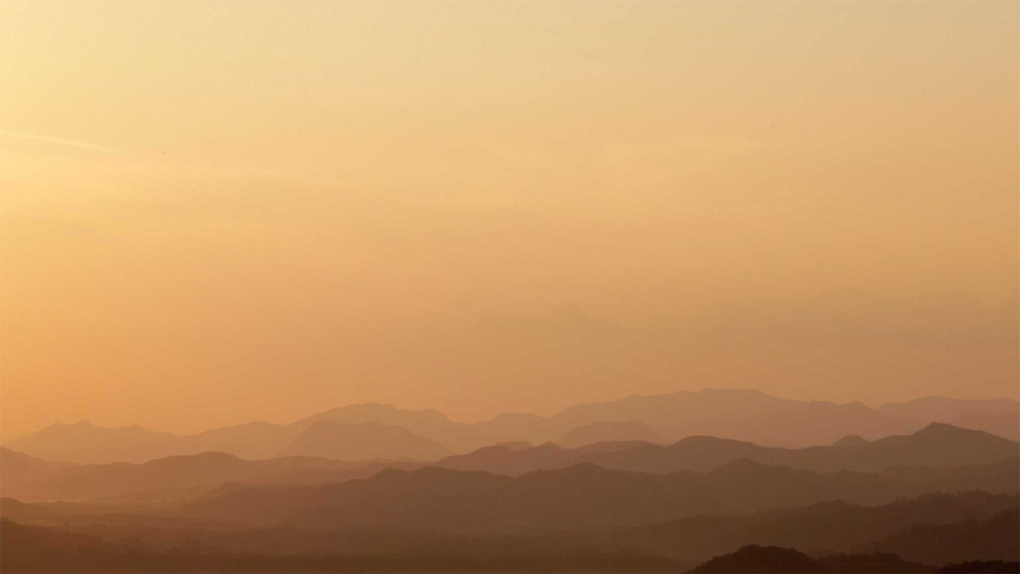Orange-bathed mountain landscape at sunset overlooking DMZ near small village Yangjiri, Cherwon, Kangwando Province, facing North Korean territory in short film ART ATTACK.