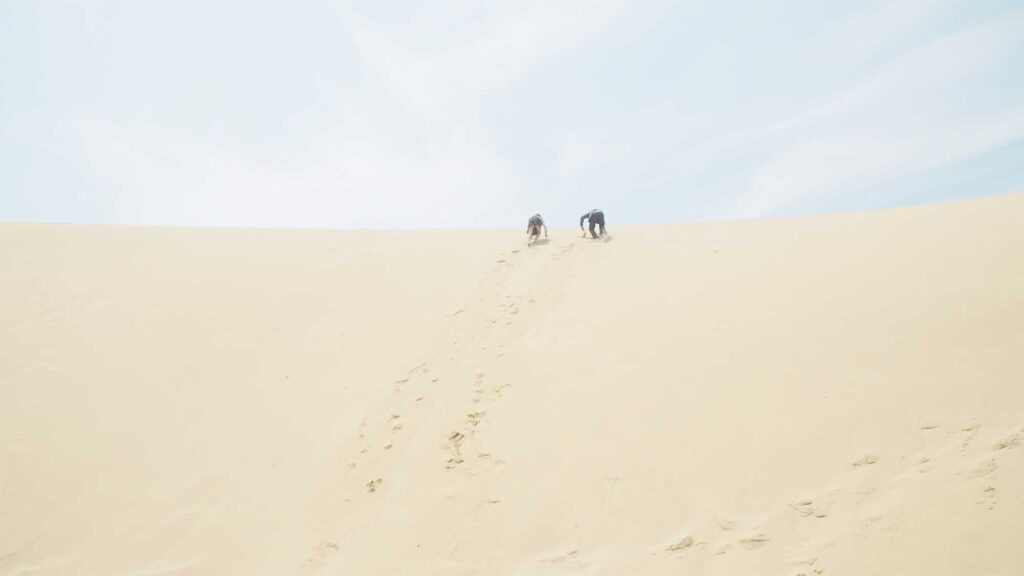 Two school children run up a large sand dune, embodying two of the lost souls from the Sewol ferry disaster in this dream sequence for the short film Last Letters.