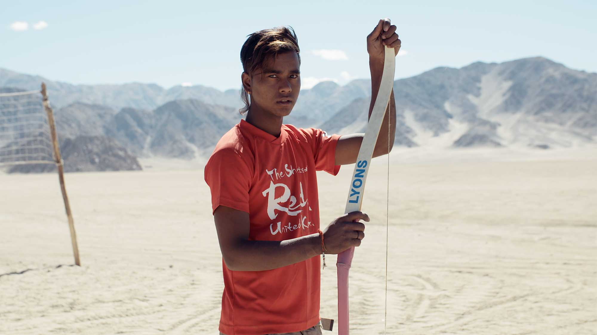 A young man from Leh, Ladakh, India, poses for a portrait holding his bow during a break from practicing archery.