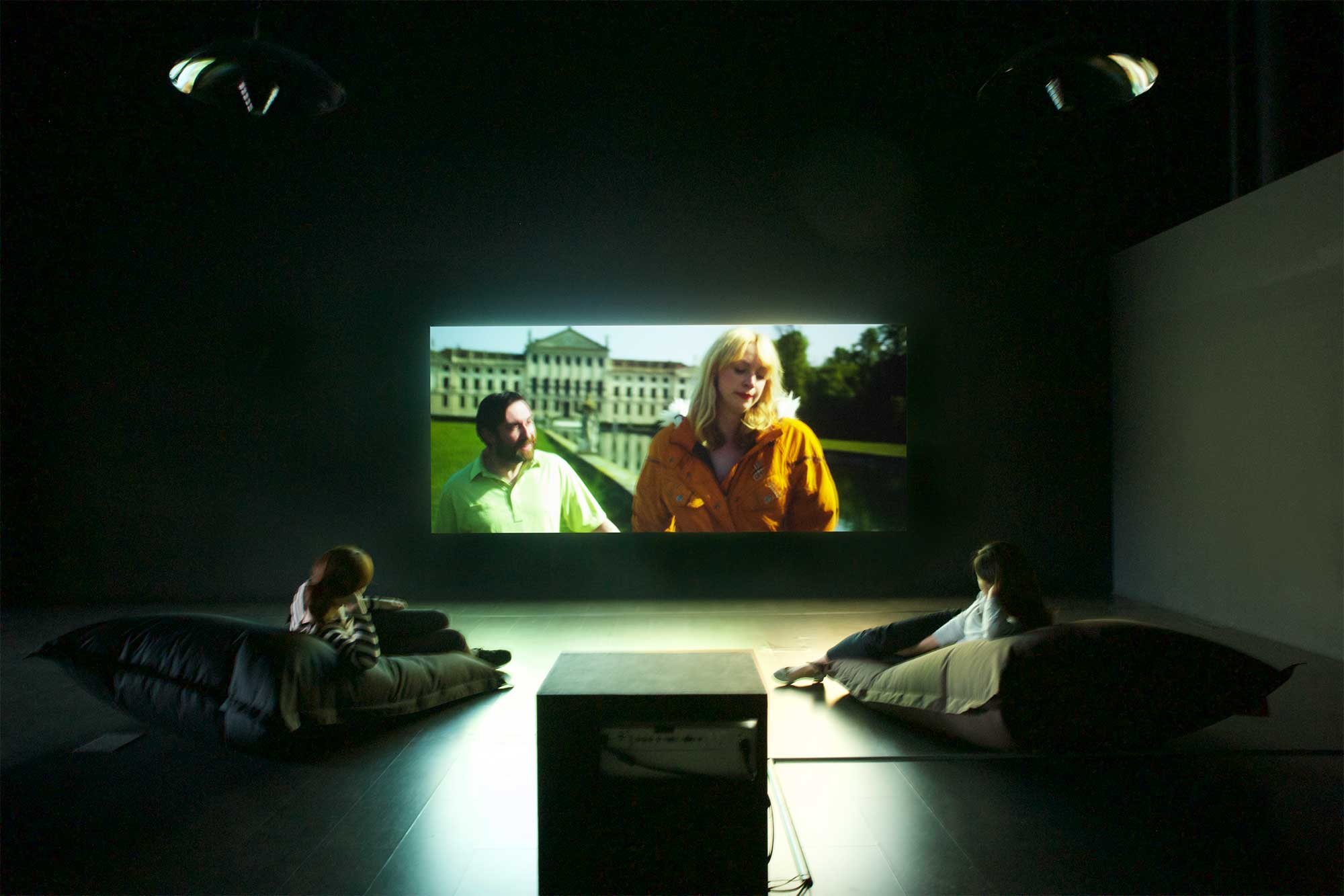 Two visitors relax on beanbags inside video installation in dark, enclosed space at SUPER-SPREADER MEDIA VIRUS exhibition, Nam June Paik Art Center, Seoul, South Korea.