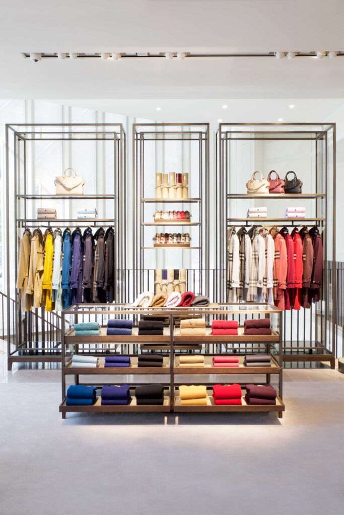 Within The Burberry Flagship Store in Seoul, South Korea, luxury fashion items are elegantly displayed on high-rising shelves, showcasing a harmonious blend of classical and modern architectural design.