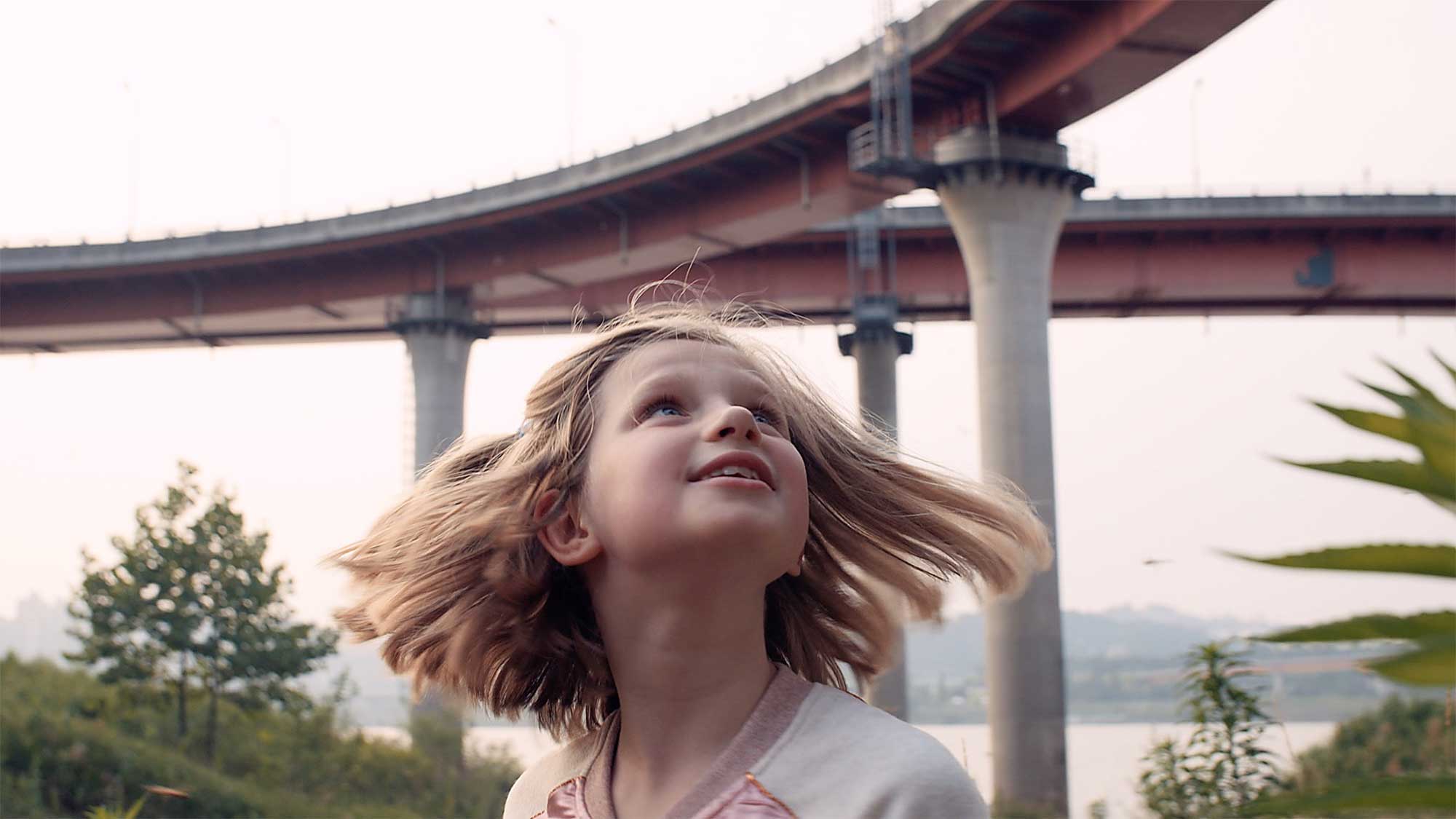 Young girl hangs out on grassland next to flyovers crossing Han River in Seoul, South Korea, fascinated by dragonflies flying around.