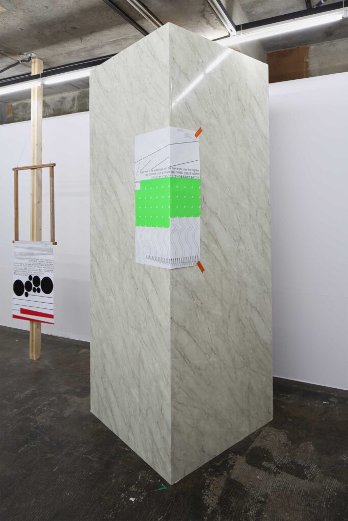 A cube adorned with a poster crossing over one of its edges, used as an installation piece for the poster exhibition in Seoul, South Korea, by Graphic Magazine as part of Propaganda Press.