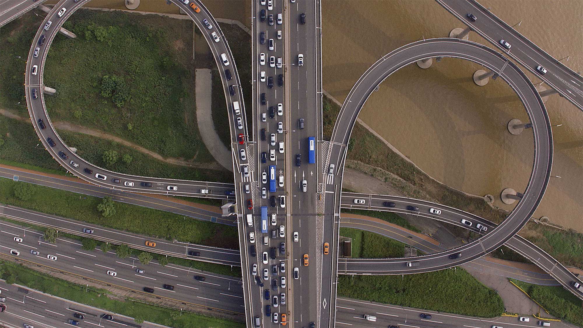Drone shot from bird's-eye perspective looking down on flyovers filled with cars as they cross Han River in Seoul, South Korea.