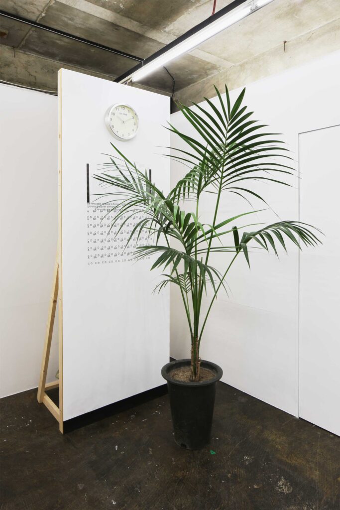 A poster pinned to a divider, partly covered by a plant, for the poster exhibition in Seoul, South Korea, by Graphic Magazine as part of Propaganda Press.