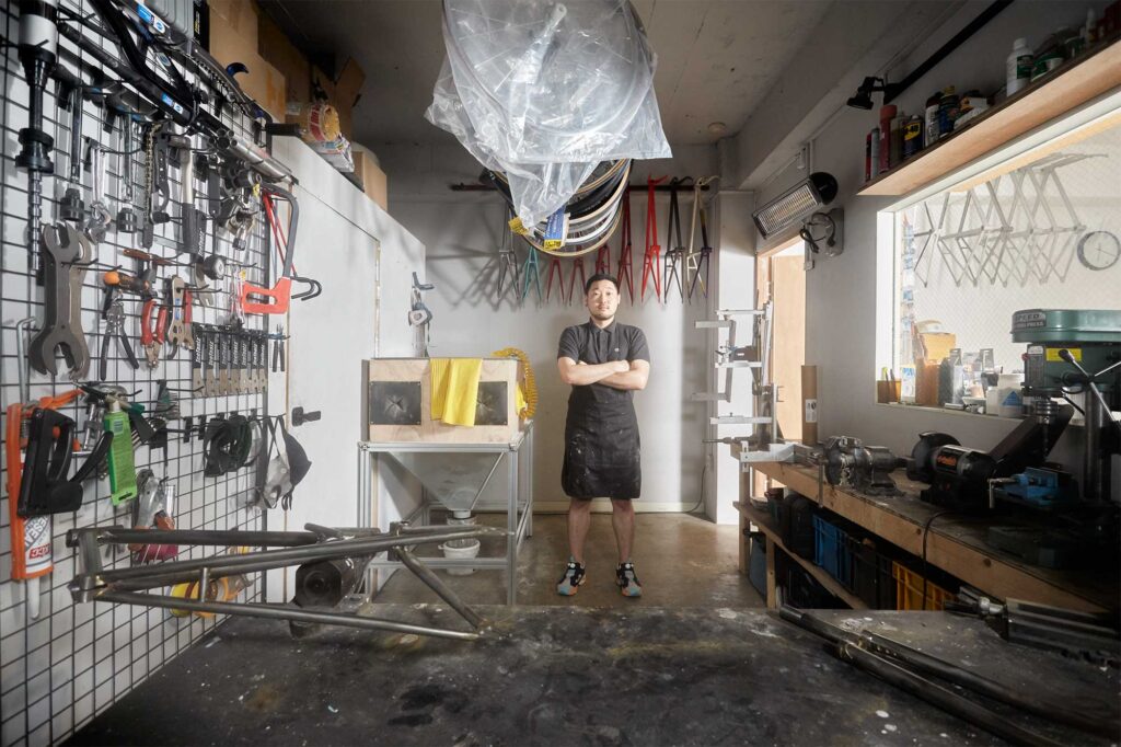 The owner of DITOBICI bicycle shop in Seoul, South Korea, showcasing custom-built road bike frames designed with elegance and style.
