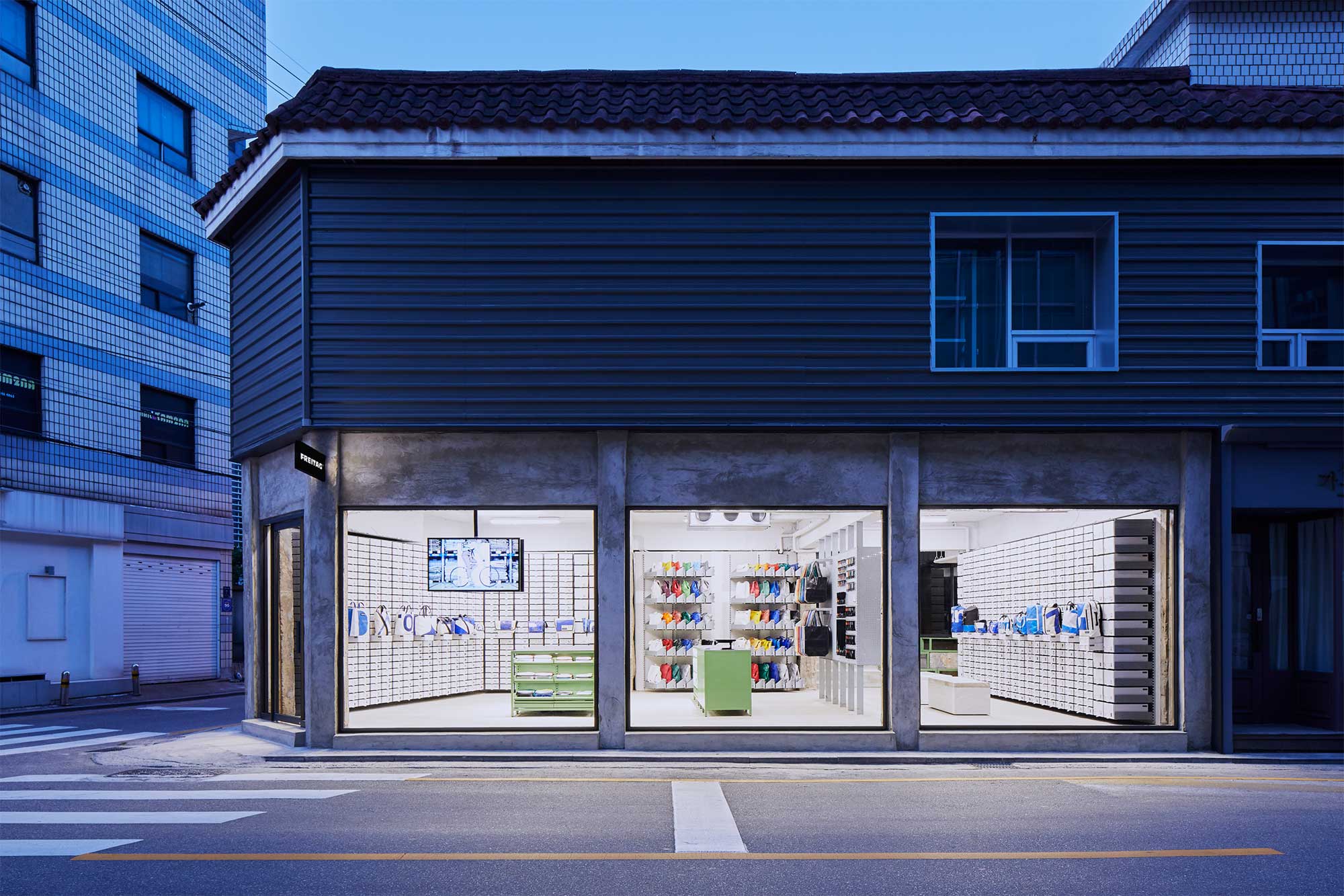 Wide frontal exterior view at dusk of Freitag Seoul Apgujeong store, designed by Schemata Architects.