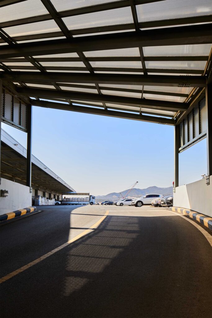 Shadows cast under covered ramp facing lot and mountains.