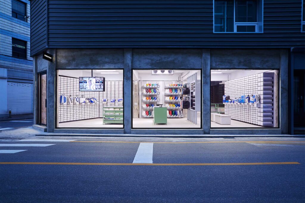 Closer frontal exterior view at dusk of Freitag Seoul Apgujeong store, designed by Schemata Architects.