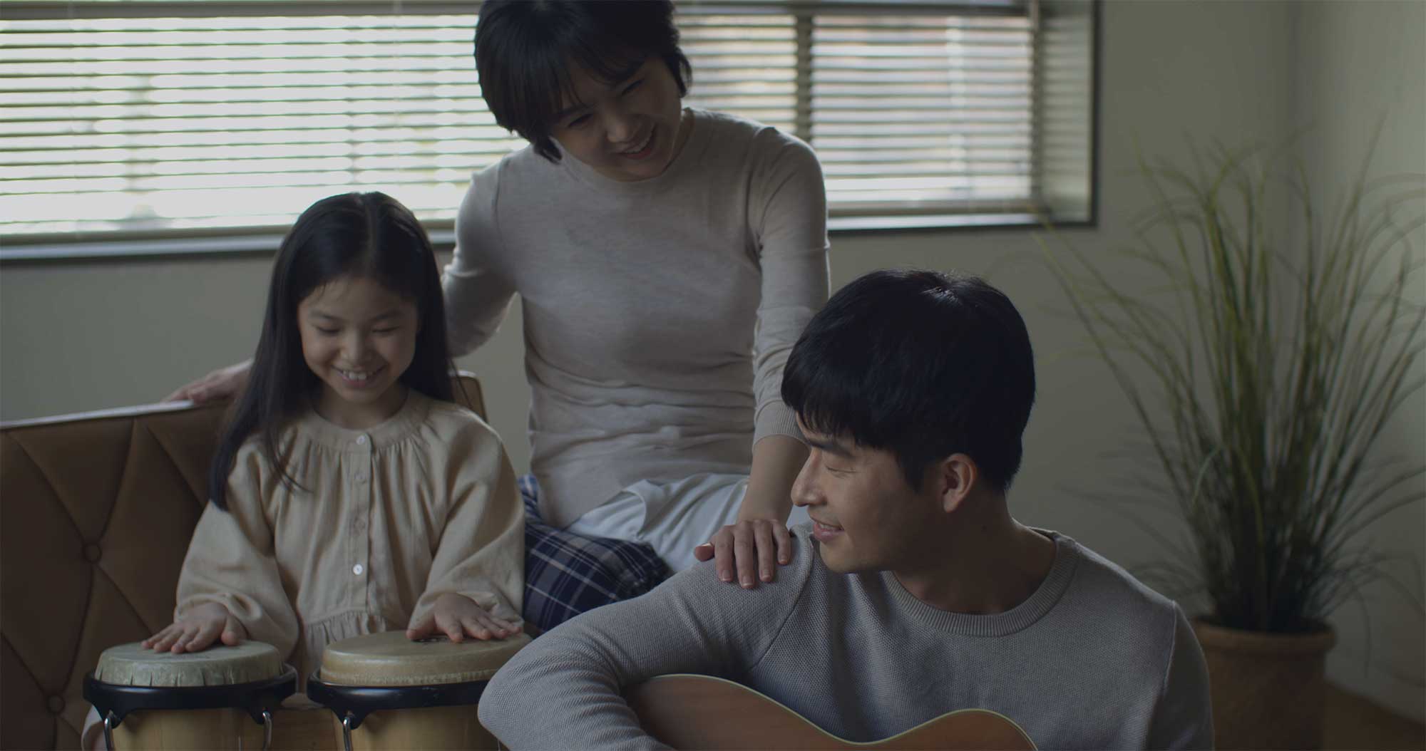 Family playing guitar and bongo together in Samsung Life Insurance video