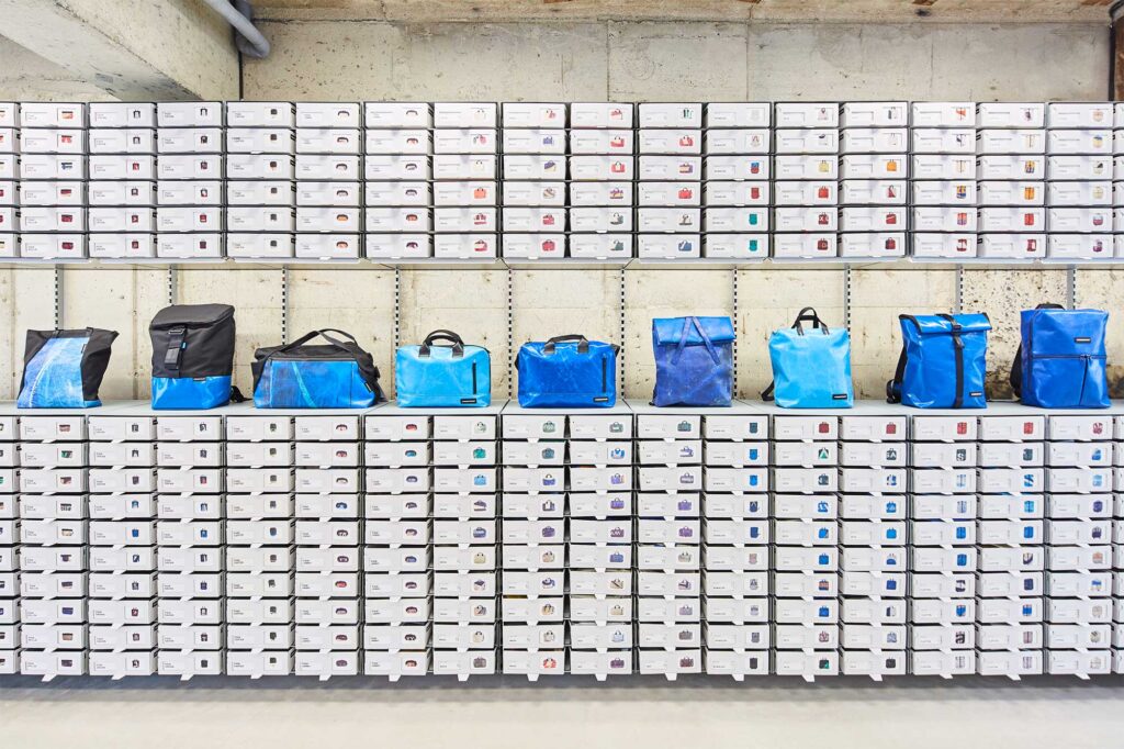 White shelf splits horizontally showcasing new blue line of Freitag bags at Jejudo store